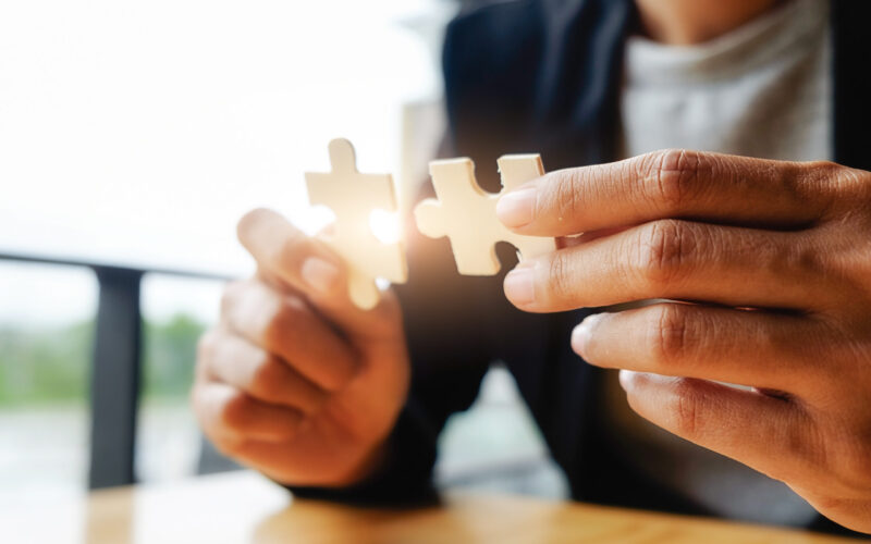 Business woman hands connecting jigsaw puzzle. Business solutions, success and strategy concept. Businessman hand connecting jigsaw puzzle.Close up photo with selective focus.